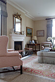 Upholstered armchair and ottoman at fireside in Pewsey living room Wiltshire England UK