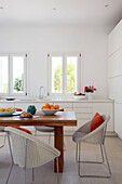 Wicker chairs at wooden table with uncurtained windows in villa on Greek island of Ithaca