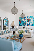 Large pendant lights and arched mirrors with modern art in living room of Greek villa on Ithaca