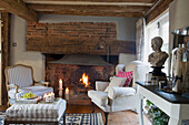 Armchairs at lit fireside in living room of Wokingham cottage Berkshire UK