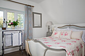 Floral bed cover on double bed with vintage towel rail in Wokingham cottage Berkshire UK