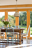 Verschiedene Stühle an einem Esstisch aus Holz mit Blick auf den Garten in einem Haus in Surrey England UK