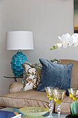 Blue velvet cushion and white lamp with sofa in living room of London townhouse England UK