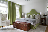 White armchair and lime green curtains in Grade II listed London townhouse bedroom England UK