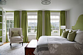 White armchair and lime green curtains in Grade II listed London townhouse bedroom England UK