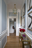 Framed artwork above brass console in light blue panelled hallway of Grade II listed London townhouse England UK
