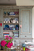 Books and crockery in dining room of Sussex country house England UK