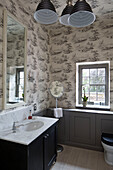 Marmorwaschbecken mit großem Spiegel im tapezierten Badezimmer eines Landhauses in Sussex, England, UK
