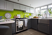 Stainless steel oven and sink in modern Surrey kitchen with lime green splashback England UK