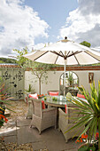 Wicker furniture under parasol in courtyard garden Dorset England UK