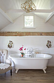 Hohes Fenster mit freiliegenden Ziegelsteinen und freistehender Badewanne in einem Haus in Dorset England UK