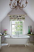 Freistehende rollende Badewanne im Fenster mit geblümten Jalousien in einem Haus in Dorset England UK