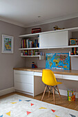 Yellow chair at desk with map and shelves in boy's room South West London UK