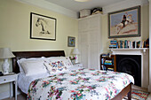 Floral duvet on double bed with books on mantlepiece in Georgian bedroom of Berkshire home England UK