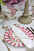 Pink striped plates on dining table in West Sussex home England UK
