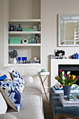 Cut tulips on ottoman with white sofa and shelving in London townhouse living room UK