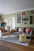 Gerahmtes Kunstwerk über dem Sofa in einem Wohnzimmer mit Holzfußboden und gemustertem Teppich in einem Haus in Großbritannien