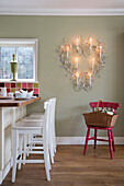 Barstools in kitchen with lit candles in wall-mounted heart in UK home