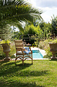 Wicker armchair in shade of palm at poolside in Var Provence France
