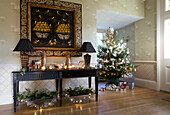 Large artwork above console with lit candles and Christmas tree in Sussex home England UK