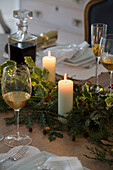 Kerzen mit Grünzeug und Weißwein auf einem Esstisch in einem Haus in Surrey, England UK
