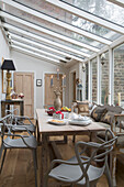 Light grey chairs at wooden table in conservatory of Surrey home England UK