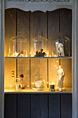 Figuren und beleuchtete Lichter auf getäfeltem Regal in einem Haus in Surrey, England, UK
