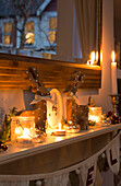 Lit candles and Christmas decorations on mantlepiece in London home England UK