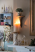 Lit candle with houseplant on wall shelf in London bedroom England UK