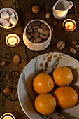 Nüsse und Früchte mit brennenden Kerzen auf einem geschnitzten Holztisch in einem Haus in Kent, England, UK