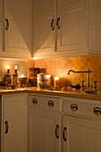 Beleuchtete Kerzen und Mehlbehälter auf der Küchenarbeitsplatte in einem Haus in Kent, England, UK