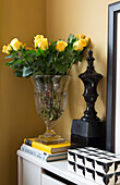 Cut roses and black ornament with books in bedroom detail of London townhouse apartment UK