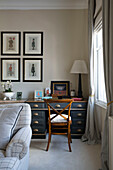 Wooden chair at desk with framed prints in London townhouse apartment UK