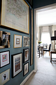 Framed map and photographs in teal hallway of London townhouse apartment UK
