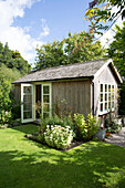 Sunlit lawn with summerhouse for extra living space in Somerset garden England UK