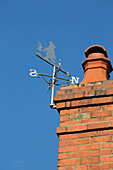 Weathervane and brick chimney on Grade II listed cottage in Hampshire England UK