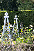 Klettergerüst und Statue mit Hecke im Garten eines Cottages in Hampshire, England, Vereinigtes Königreich