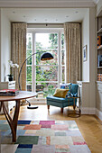 Black lamp and chair at garden window in Victorian terraced house London England UK