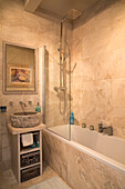 Cremefarbenes Badezimmer mit Duschwand und Waschtisch in einem Haus in Sussex, England, UK