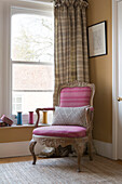 Rosa gepolsterter Sessel am Schiebefenster in einem Haus in Sussex, England, Vereinigtes Königreich