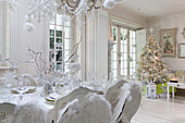 Dining chairs decorated with angel wings at table in open plan room with Christmas tree in South London home England UK