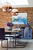 Modern exposed brick dining room with copper pendant shades in Sussex home England UK