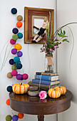 Cut flowers on stack of books with multicoloured baubles in London home England UK