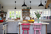 Painted pink bar stools in open plan Sussex kitchen England UK