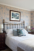 Seascape above brass vintage bed in Sussex home England UK