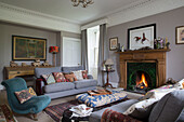 Low ottoman and upholstered antique chair in Kelso living room with lit fire Scotland UK
