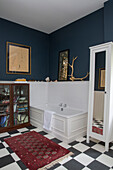 White panelled bath with glass fronted cabinet in dark blue Kelso bathroom Scotland UK