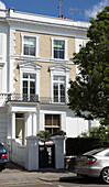 Cars parked outside three storey London townhouse with white paintwork England UK