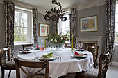 Runder Tisch für sechs Personen im Esszimmer mit Blattvorhängen in einem Bauernhaus in Gloucestershire England UK