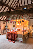 Lit lights on four-poster bed with co-ordinating fabrics in Hampshire farmhouse England UK